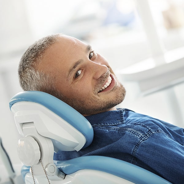 A mature man in the dentist's office waiting for his dental exam while smiling