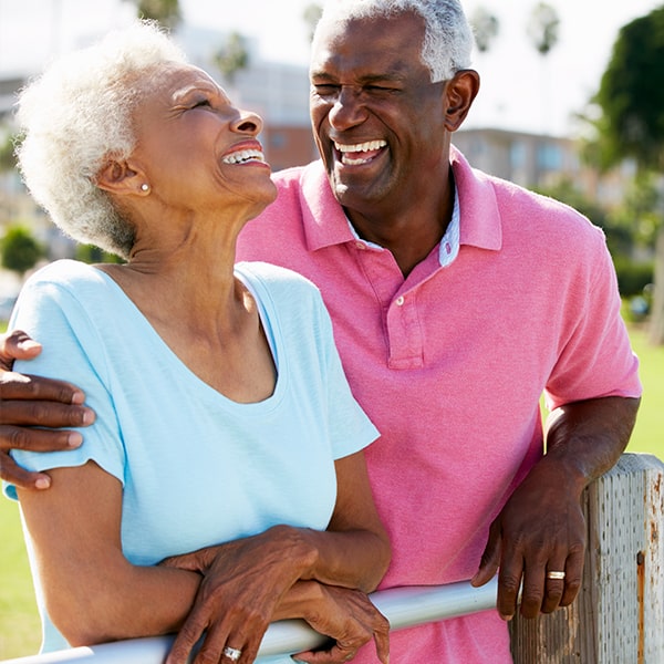 An older couple smiling as they hug