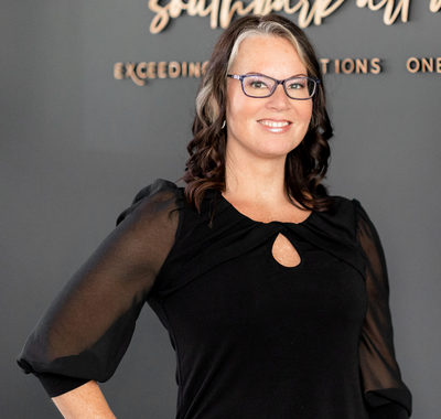 Woman in a black dress wearing glasses and smiling